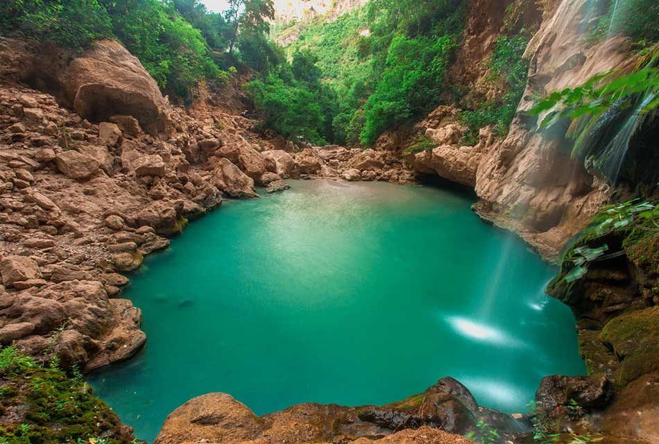 Crystal-clear waters of Akchour reflecting the surrounding mountains and trees.