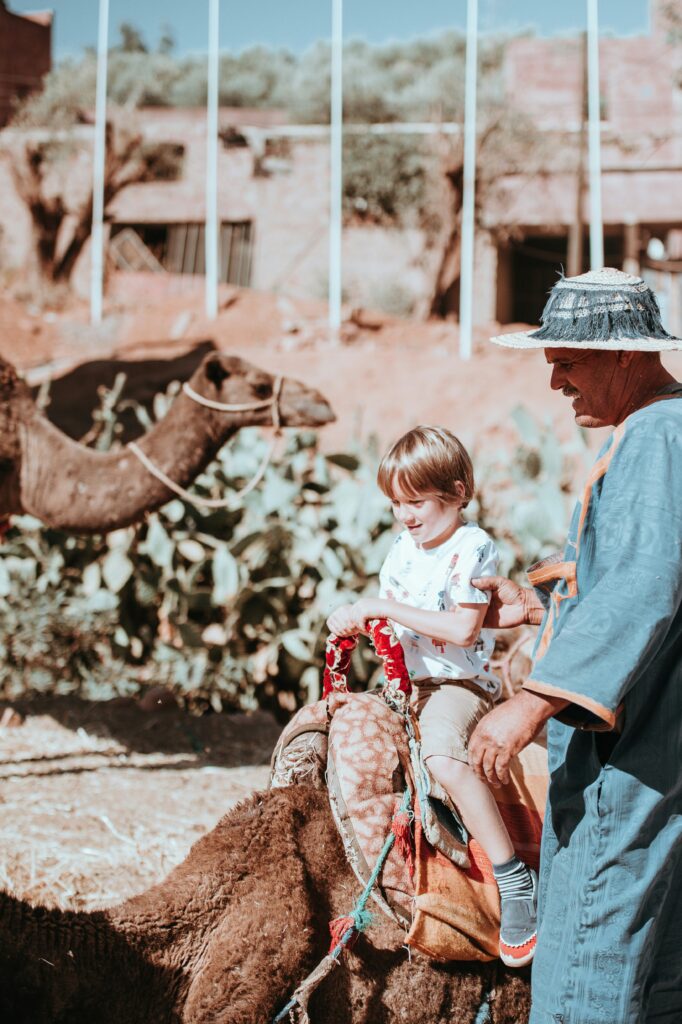 hild riding a camel during an affordable family travel adventure in Morocco.