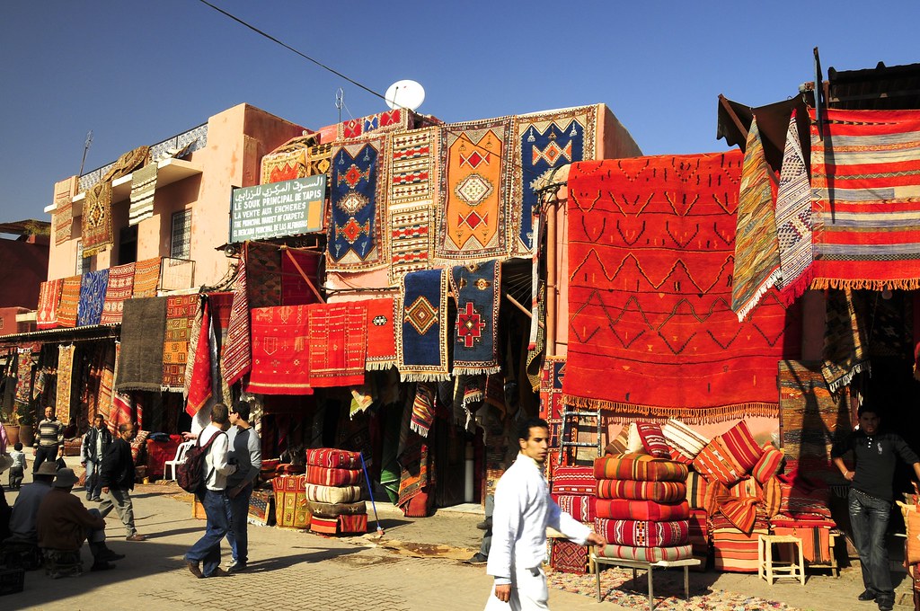 Souk Zarbia in Marrakech showcasing a variety of authentic Moroccan rugs and textiles, capturing the vibrant market atmosphere.