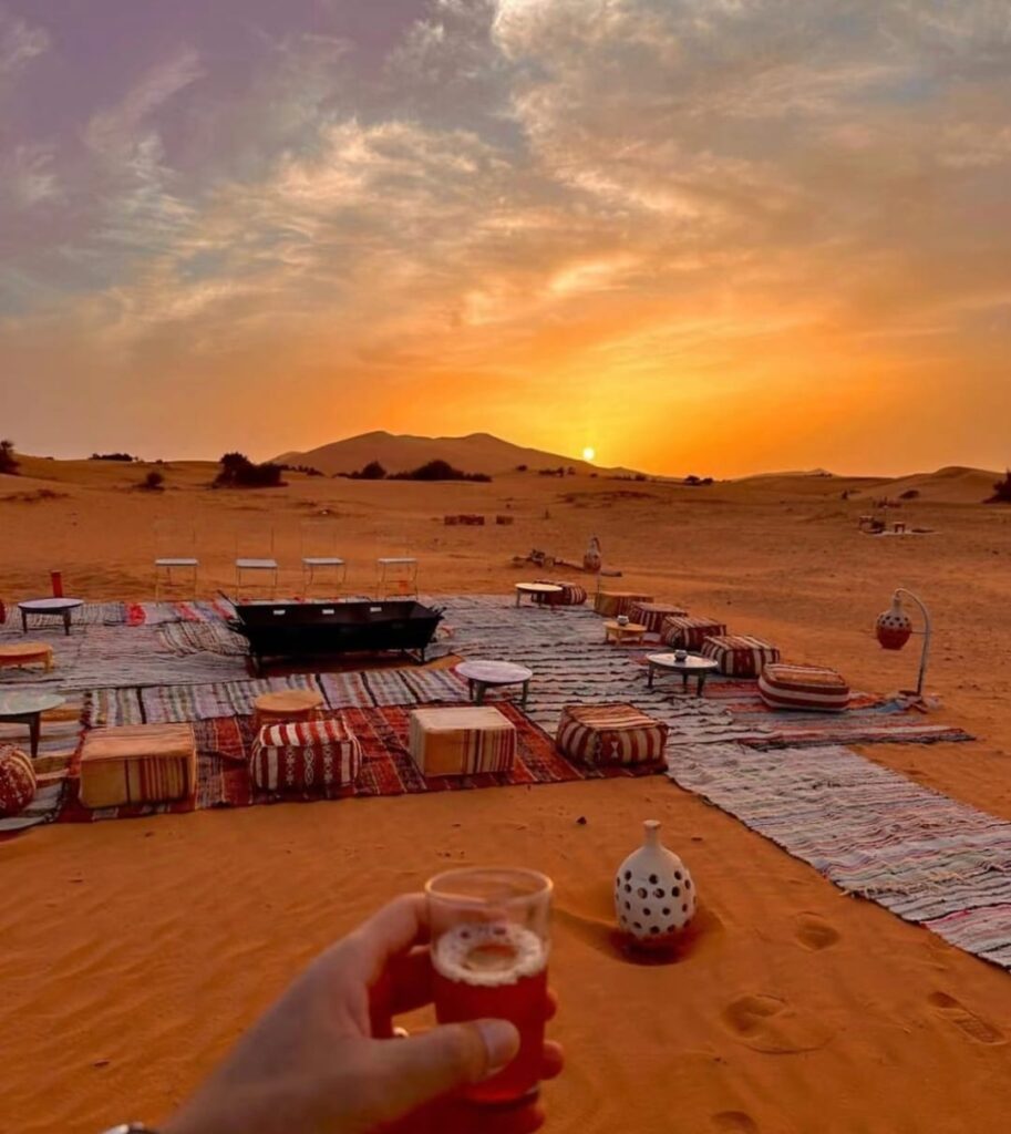 A couple stargazing under the night sky in the Sahara Desert, one of the most romantic spots in Morocco, surrounded by tranquil sand dunes and a blanket of stars.