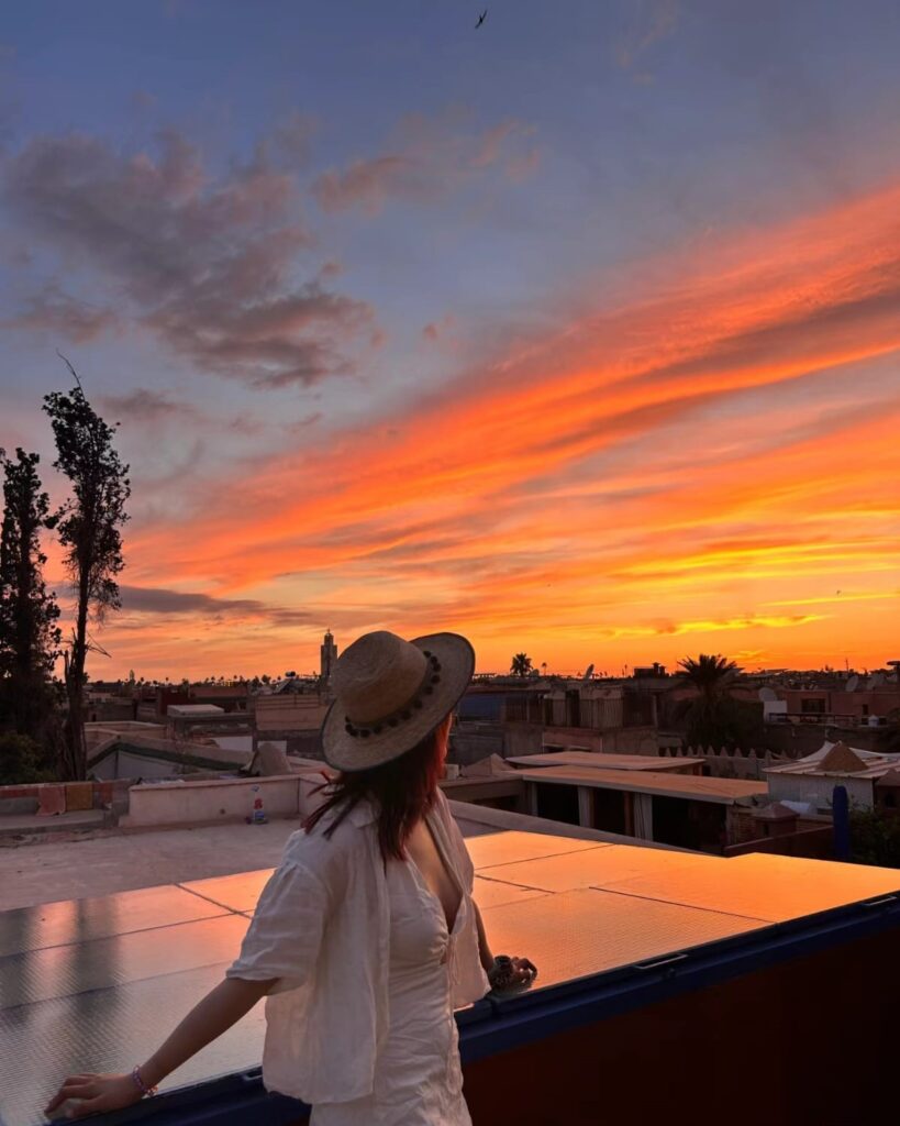 A breathtaking sunset sky over Marrakech, casting warm hues of orange and pink, creating a romantic atmosphere perfect for couples exploring the vibrant city in romantic Morocco.